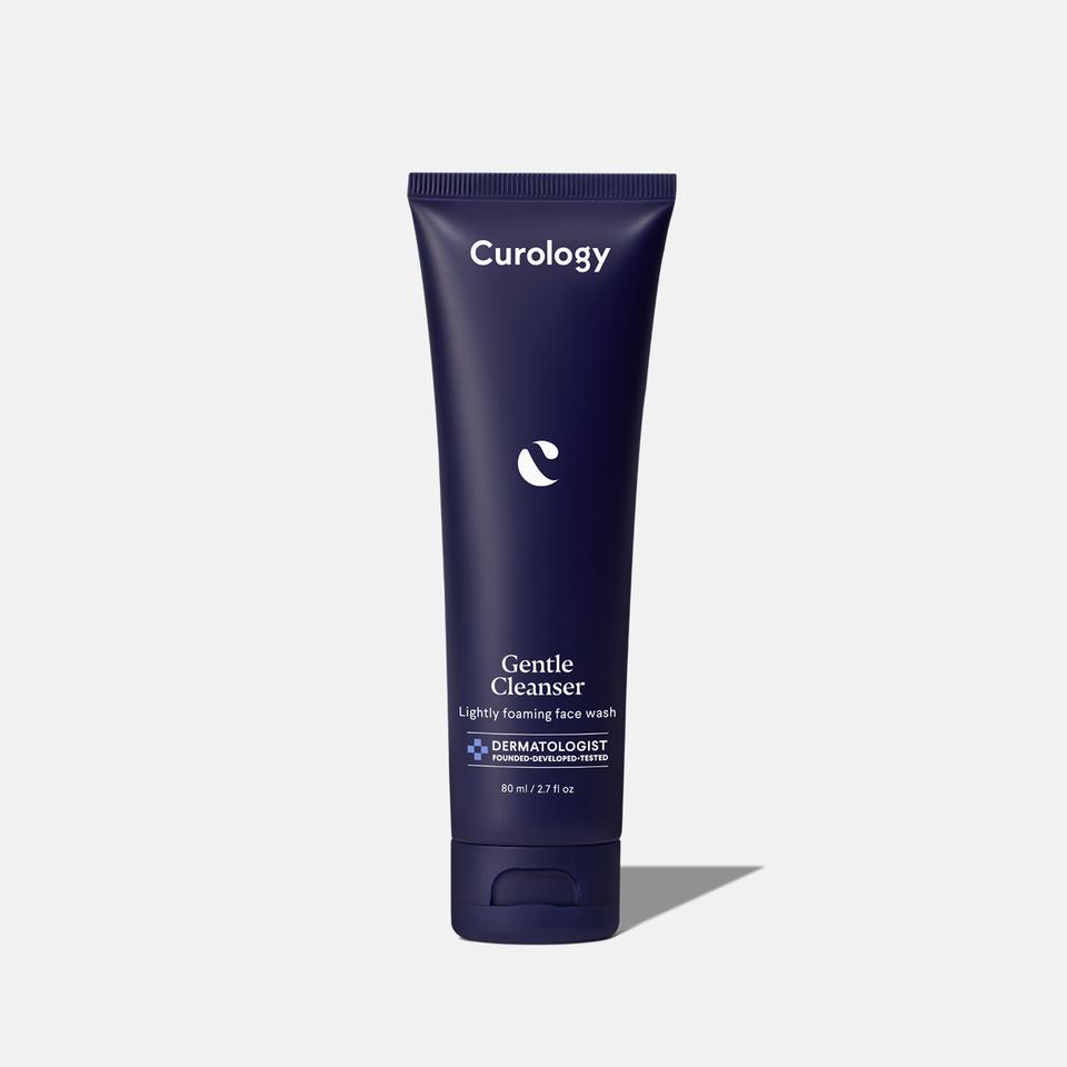 Curology Gentle Cleanser in a dark blue squeeze tube with flip-top cap, labeled ‘Lightly foaming face wash,’ dermatologist founded, developed, and tested.