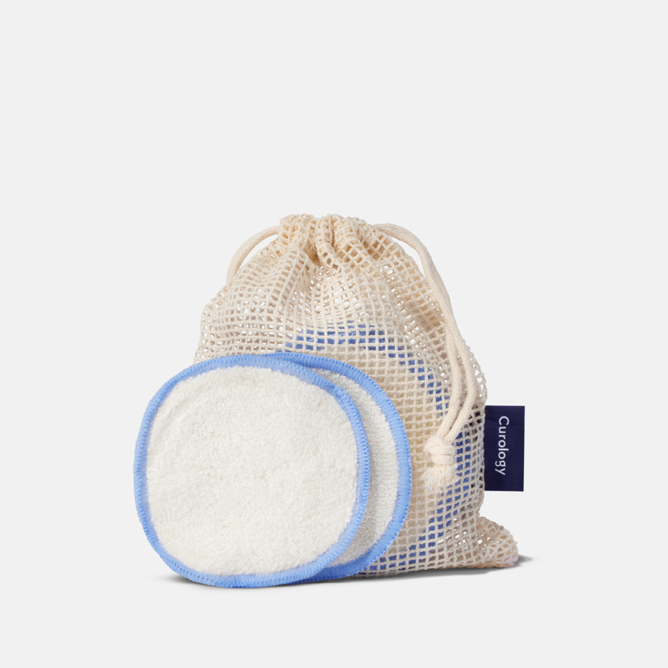 Curology reusable cotton rounds shown in a natural mesh drawstring bag, featuring soft white pads with light blue trim for gentle cleansing and makeup removal.
